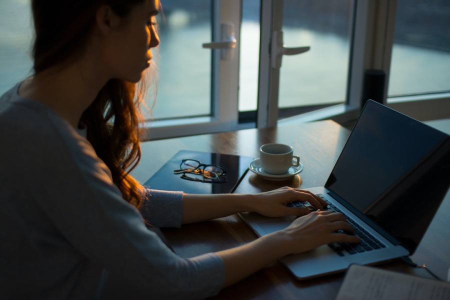 Business professional sitting at a desk with coffee and using laptop to review data on a pyramid chart